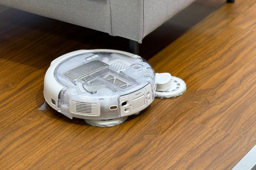 DJI ROMO 2 Roboterarm mit ausgefahrenem Wischmopp an einer Möbelkante